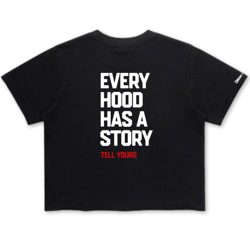 A black short-sleeve crop top t-shirt with bold white text reading 'EVERY HOOD HAS A STORY' and smaller red text 'TELL YOURS' underneath, shown flat against a white background.