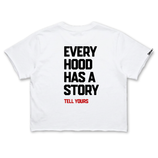 A white short-sleeve crop top t-shirt with bold black text reading 'EVERY HOOD HAS A STORY' and smaller red text reading 'TELL YOURS' underneath, shown flat against a white background.