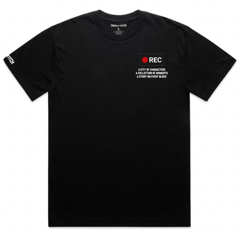 A black short-sleeve t-shirt with a small graphic on the left chest featuring a red circle and the text 'REC A CITY OF CHARACTERS A COLLECTION OF MEMORIES A STORY ON EVERY BLOCK'. The right sleeve has 'REC' printed in white.