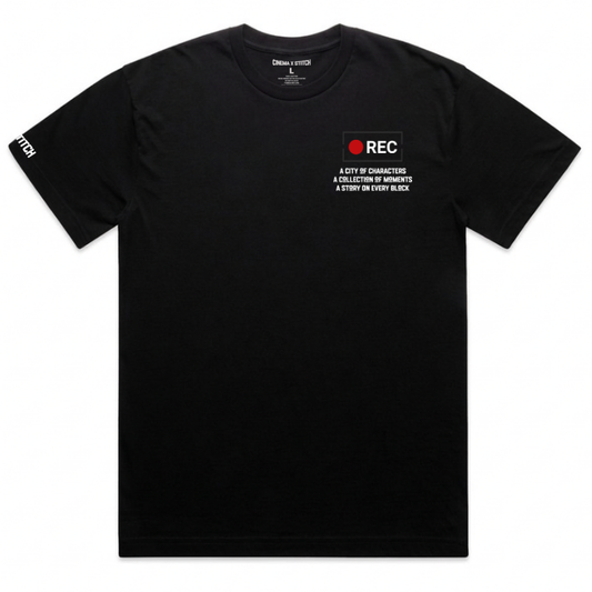 A black short-sleeve t-shirt with a small graphic on the left chest featuring a red circle and the text 'REC A CITY OF CHARACTERS A COLLECTION OF MEMORIES A STORY ON EVERY BLOCK'. The right sleeve has 'REC' printed in white.