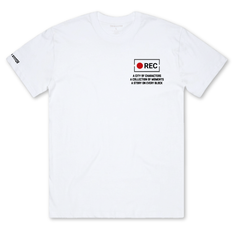 A white short-sleeve crewneck t-shirt featuring a black and red graphic on the left chest with the text 'REC A CITY OF CHARACTERS A COLLECTION OF MEMORIES A STORY ON EVERY BLICK' and 'REC' with a red circle. A small black sleeve print is visible on the right sleeve.