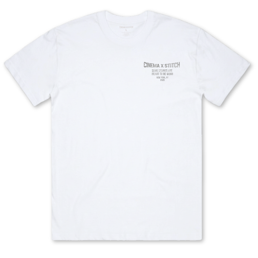A white short-sleeve crewneck t-shirt with a small gray graphic print on the left chest reading 'CINEMA x STITCH'.